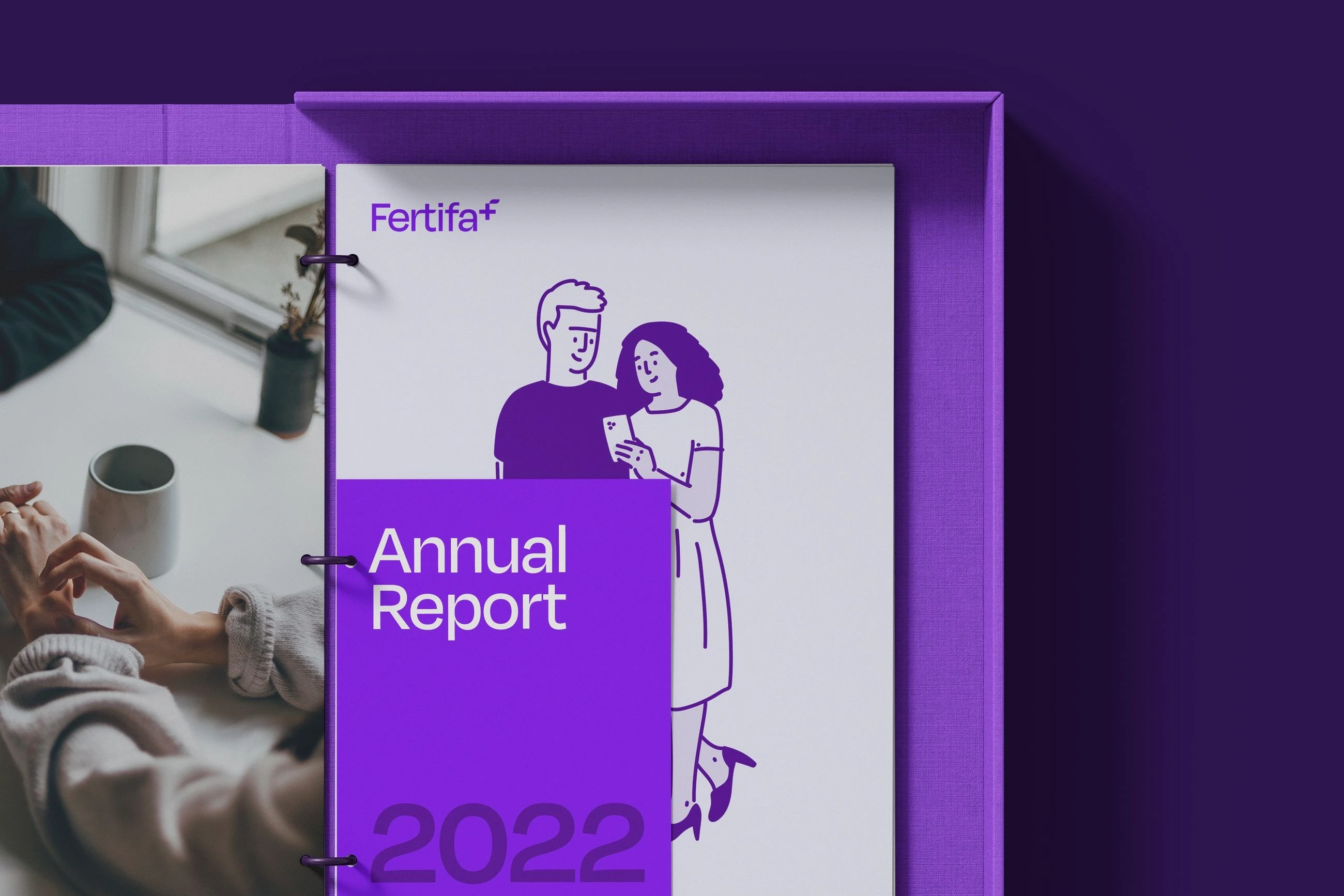 Fertifa’s 2022 annual report in a purple box file: a line illustration of a couple on the cover, beside a photo of hands around a mug