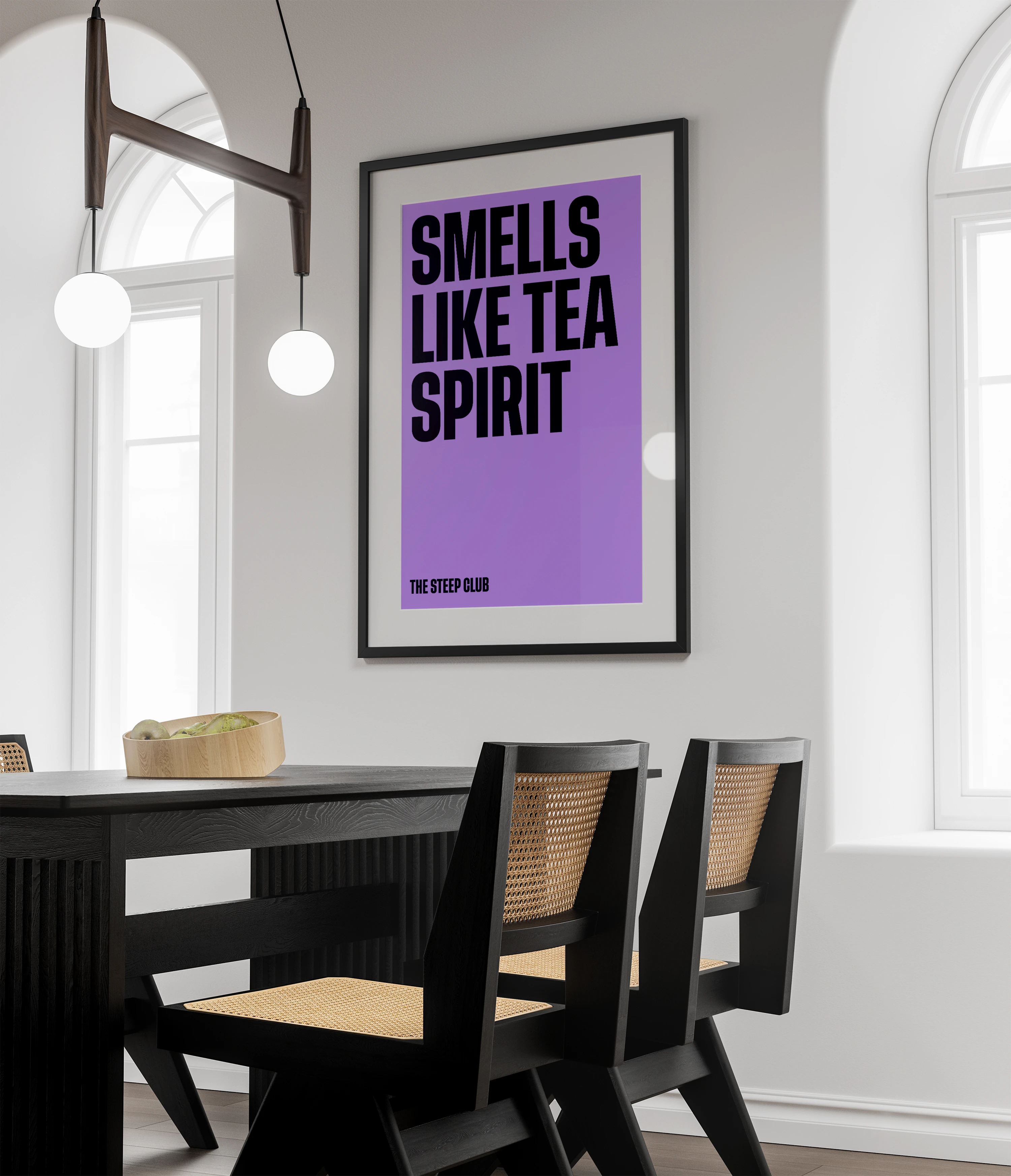 A framed purple poster, “Smells like tea spirit”, above a dark dining table with cane-backed chairs