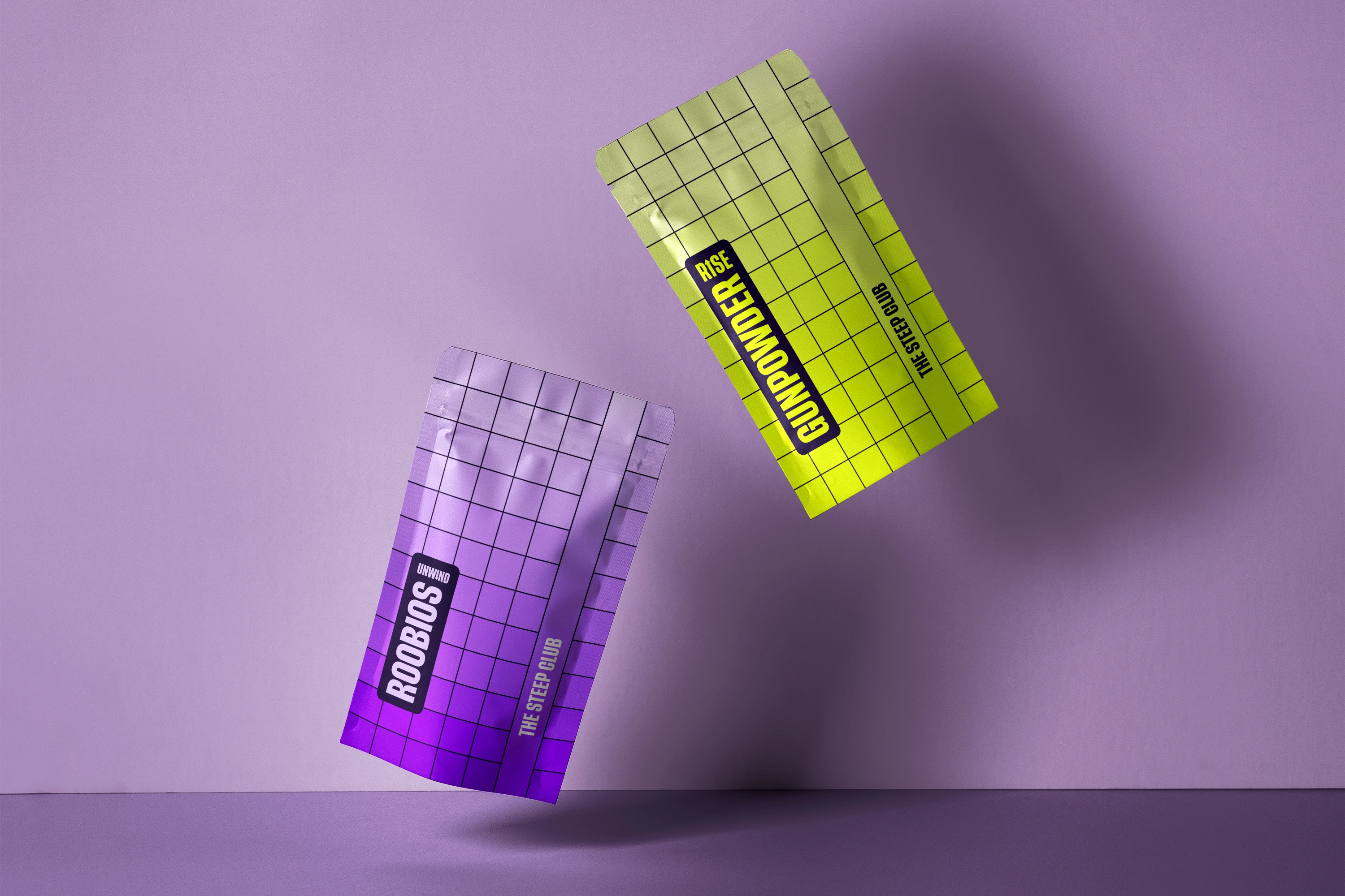 A purple Unwind pouch and an acid yellow Rise pouch falling against a lilac wall, both printed with the same black grid