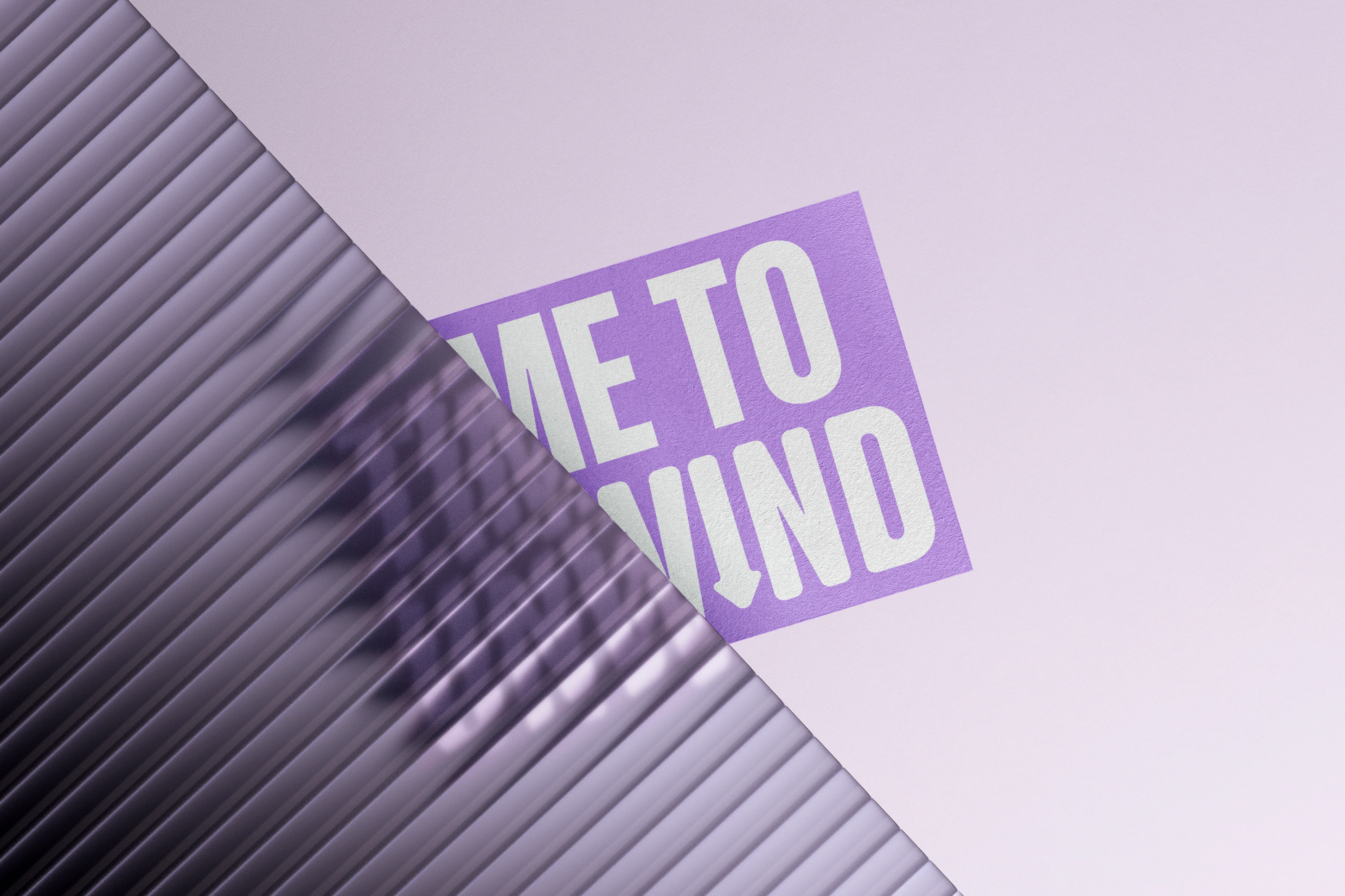 A purple “Time to Unwind” sticker seen half through a sheet of reeded glass, the letters breaking up behind the ridges